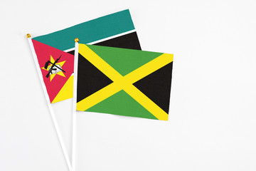 Jamaica and Mozambique stick flags on white background. High quality fabric, miniature national flag. Peaceful global concept.White floor for copy space.