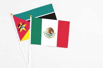 Mexico and Mozambique stick flags on white background. High quality fabric, miniature national flag. Peaceful global concept.White floor for copy space.