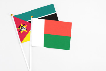 Madagascar and Mozambique stick flags on white background. High quality fabric, miniature national flag. Peaceful global concept.White floor for copy space.