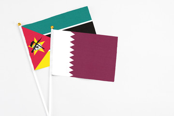 Qatar and Mozambique stick flags on white background. High quality fabric, miniature national flag. Peaceful global concept.White floor for copy space.