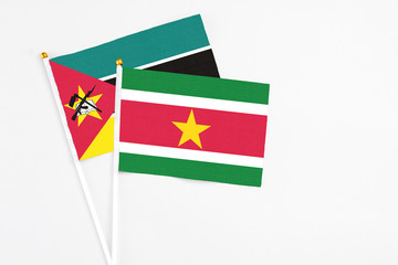 Suriname and Mozambique stick flags on white background. High quality fabric, miniature national flag. Peaceful global concept.White floor for copy space.