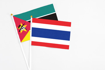Thailand and Mozambique stick flags on white background. High quality fabric, miniature national flag. Peaceful global concept.White floor for copy space.