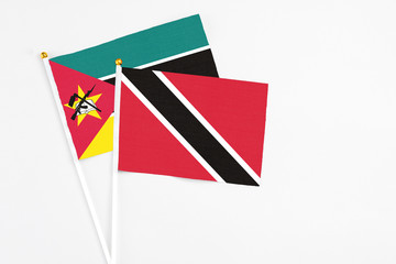 Trinidad And Tobago and Mozambique stick flags on white background. High quality fabric, miniature national flag. Peaceful global concept.White floor for copy space.