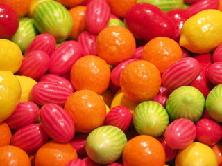 Fototapeta na wymiar Close up of bowls filled with a large selection of different colored soft candies. Green, Orange, Red and yellow candies