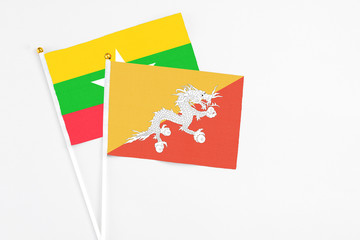 Bhutan and Myanmar stick flags on white background. High quality fabric, miniature national flag. Peaceful global concept.White floor for copy space.