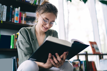 Glad woman in glasses reading interesting story
