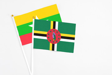 Dominica and Myanmar stick flags on white background. High quality fabric, miniature national flag. Peaceful global concept.White floor for copy space.