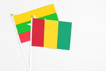 Guinea and Myanmar stick flags on white background. High quality fabric, miniature national flag. Peaceful global concept.White floor for copy space.