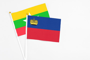 Liechtenstein and Myanmar stick flags on white background. High quality fabric, miniature national flag. Peaceful global concept.White floor for copy space.