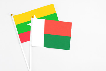 Madagascar and Myanmar stick flags on white background. High quality fabric, miniature national flag. Peaceful global concept.White floor for copy space.