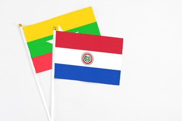 Paraguay and Myanmar stick flags on white background. High quality fabric, miniature national flag. Peaceful global concept.White floor for copy space.
