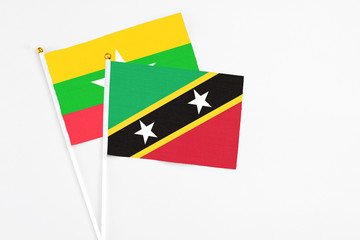 Saint Kitts And Nevis and Myanmar stick flags on white background. High quality fabric, miniature national flag. Peaceful global concept.White floor for copy space.