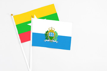 San Marino and Myanmar stick flags on white background. High quality fabric, miniature national flag. Peaceful global concept.White floor for copy space.