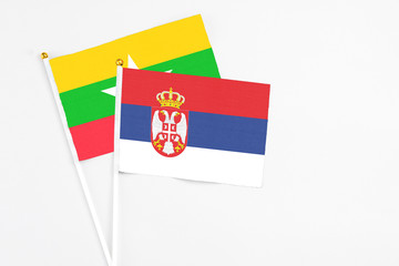 Serbia and Myanmar stick flags on white background. High quality fabric, miniature national flag. Peaceful global concept.White floor for copy space.