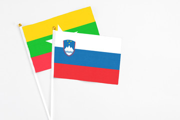 Slovenia and Myanmar stick flags on white background. High quality fabric, miniature national flag. Peaceful global concept.White floor for copy space.