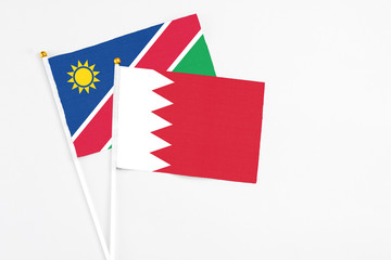 Bahrain and Namibia stick flags on white background. High quality fabric, miniature national flag. Peaceful global concept.White floor for copy space.