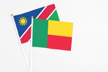 Benin and Namibia stick flags on white background. High quality fabric, miniature national flag. Peaceful global concept.White floor for copy space.