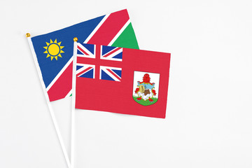 Fototapeta premium Bermuda and Namibia stick flags on white background. High quality fabric, miniature national flag. Peaceful global concept.White floor for copy space.