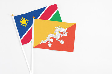 Bhutan and Namibia stick flags on white background. High quality fabric, miniature national flag. Peaceful global concept.White floor for copy space.
