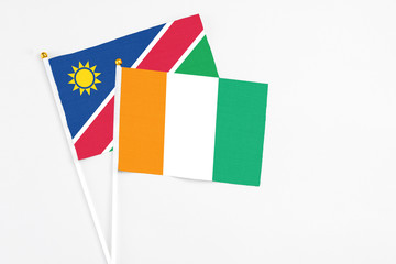 Cote D'Ivoire and Namibia stick flags on white background. High quality fabric, miniature national flag. Peaceful global concept.White floor for copy space.