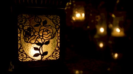 Roses on stained glass jar backlit by candle, soft focus candles in background - Powered by Adobe
