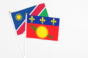 Guadeloupe and Namibia stick flags on white background. High quality fabric, miniature national flag. Peaceful global concept.White floor for copy space.