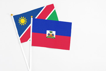 Haiti and Namibia stick flags on white background. High quality fabric, miniature national flag. Peaceful global concept.White floor for copy space.