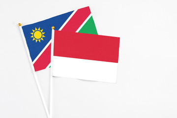 Monaco and Namibia stick flags on white background. High quality fabric, miniature national flag. Peaceful global concept.White floor for copy space.