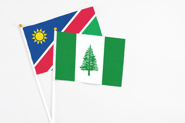 Norfolk Island and Namibia stick flags on white background. High quality fabric, miniature national flag. Peaceful global concept.White floor for copy space.
