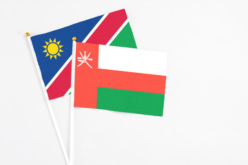 Oman and Namibia stick flags on white background. High quality fabric, miniature national flag. Peaceful global concept.White floor for copy space.