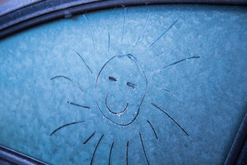 The sun is painted on the frozen glass of the car. The sun smiles