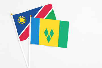 Saint Vincent And The Grenadines and Namibia stick flags on white background. High quality fabric, miniature national flag. Peaceful global concept.White floor for copy space.