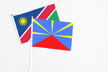 Fototapeta na wymiar Reunion and Namibia stick flags on white background. High quality fabric, miniature national flag. Peaceful global concept.White floor for copy space.