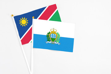 San Marino and Namibia stick flags on white background. High quality fabric, miniature national flag. Peaceful global concept.White floor for copy space.