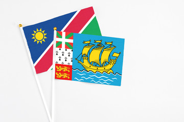 Saint Pierre And Miquelon and Namibia stick flags on white background. High quality fabric, miniature national flag. Peaceful global concept.White floor for copy space.