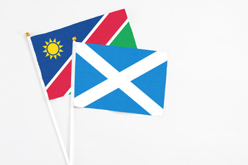 Fototapeta na wymiar Scotland and Namibia stick flags on white background. High quality fabric, miniature national flag. Peaceful global concept.White floor for copy space.
