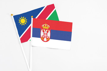 Serbia and Namibia stick flags on white background. High quality fabric, miniature national flag. Peaceful global concept.White floor for copy space.