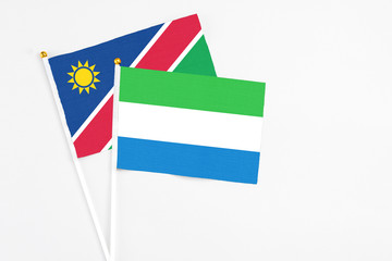 Sierra Leone and Namibia stick flags on white background. High quality fabric, miniature national flag. Peaceful global concept.White floor for copy space.