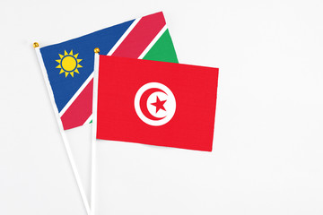 Tunisia and Namibia stick flags on white background. High quality fabric, miniature national flag. Peaceful global concept.White floor for copy space.