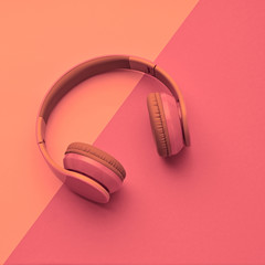 Minimal fashion, Trendy headphones. Music vibration on pink geometry background. Hipster DJ accessory Flat lay. Art creative summer vibes fashionable pop art style. Sweet pastel color, gel filter