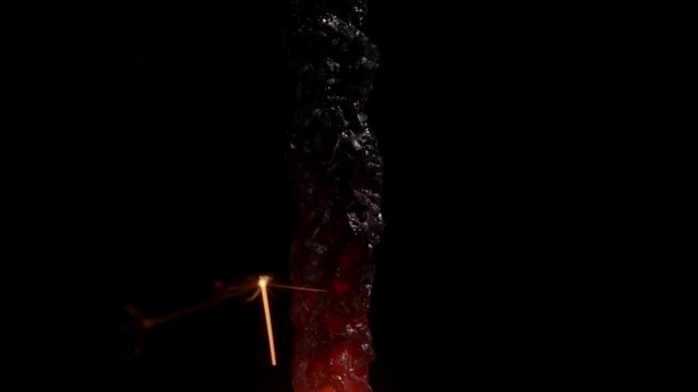 Macro shot of the toxic charcoaled remains of a burning golden sparkler with melting glowing red hot ambers.
