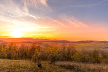 Sunset overlooking nature and landscape from Brno hill sunset couple of moments before sunset orange color with clouds moving in the background and planes flying in the sky.