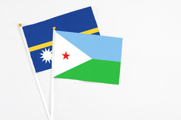 Djibouti and Nauru stick flags on white background. High quality fabric, miniature national flag. Peaceful global concept.White floor for copy space.