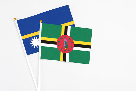 Dominica and Nauru stick flags on white background. High quality fabric, miniature national flag. Peaceful global concept.White floor for copy space.
