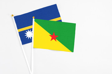 French Guiana and Nauru stick flags on white background. High quality fabric, miniature national flag. Peaceful global concept.White floor for copy space.