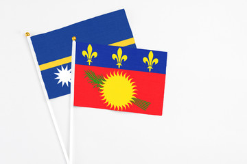 Guadeloupe and Nauru stick flags on white background. High quality fabric, miniature national flag. Peaceful global concept.White floor for copy space.