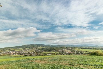 Fototapeta na wymiar Moving clouds in two directions, above the village of the Krhova Beskydy Czech republic looking at horizon around with visible hills and mountains during sunny days and field for crop