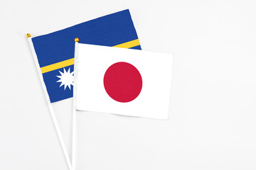 Japan and Nauru stick flags on white background. High quality fabric, miniature national flag. Peaceful global concept.White floor for copy space.