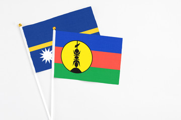 New Caledonia and Nauru stick flags on white background. High quality fabric, miniature national flag. Peaceful global concept.White floor for copy space.