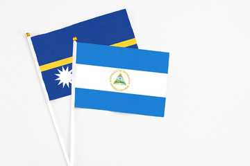 Nicaragua and Nauru stick flags on white background. High quality fabric, miniature national flag. Peaceful global concept.White floor for copy space.